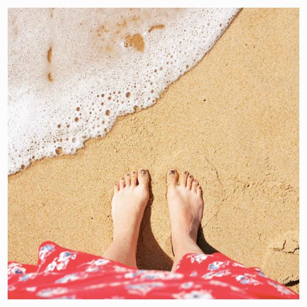 Blogueuse les pieds dans le sable à la plage
