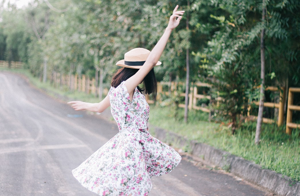 Femme avec une robe fleurie qui danse sur une route