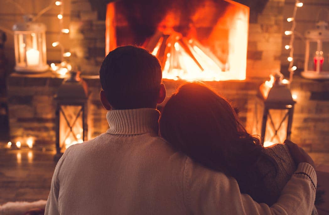 Couple s'enlacant devant un feu de cheminée